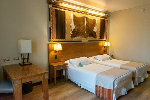 Habitación de hotel con 2 camas y mesa en Alejandro 1º Hotel en Salta