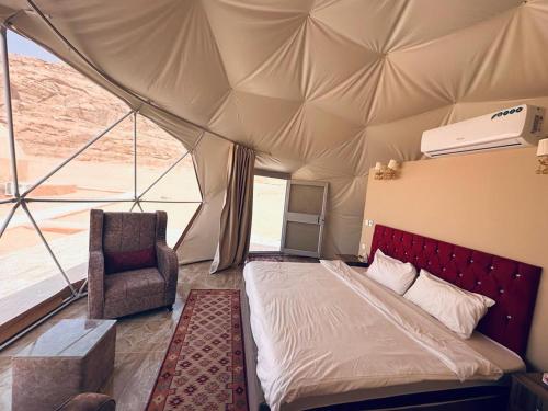 um quarto com uma cama e uma cadeira numa tenda em Wadi Rum Aviva camp em Wadi Rum