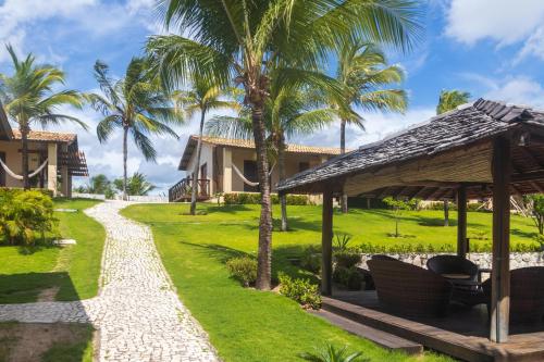 a pathway leading to a resort with palm trees at Hotel Villaggio Tudo Bom in Uruau