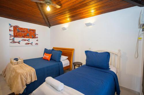 two beds in a room with blue and orange pillows at Casa com Vista Mar e 2 Suítes | CBR 07 in Búzios