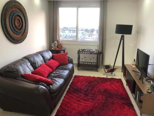 a living room with a leather couch and a red rug at Buenos Aires 705 in Osório