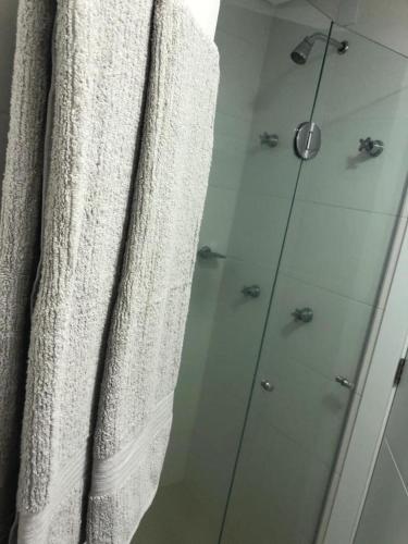 a bathroom with a shower and a white towel at Buenos Aires 705 in Osório