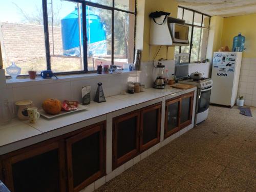 a kitchen with a counter with a stove and a refrigerator at Hospedaje Cora in Piura