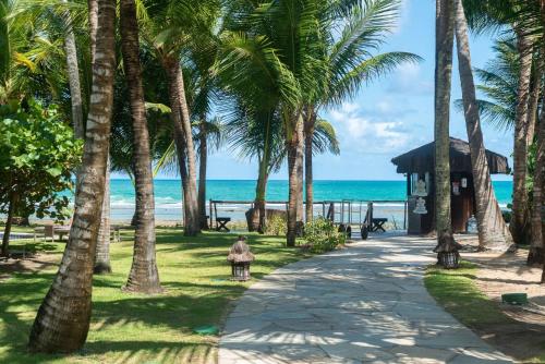 eine Frau, die einen Weg neben dem Strand entlang geht in der Unterkunft Nannai Residence Muro Alto Porto de Galinhas Beira Mar in Porto De Galinhas