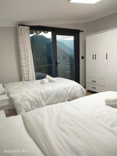 a bedroom with two beds and a large window at LEYLİ GABAN VİLLA in Çaykara