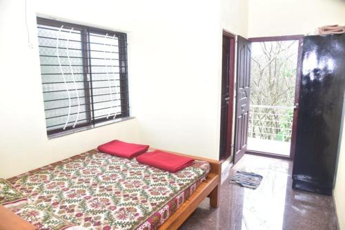a room with a bed with two red pillows on it at Devatha Homestay, Guest House, Hotel,Dharmasthala-2 in Dharmastala