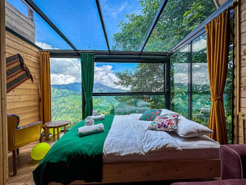 Schlafzimmer mit einem Bett vor einem großen Fenster in der Unterkunft Organic village bungalow in Ayder Yaylasi