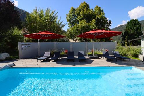 una piscina con 2 sombrillas y sillas y una piscina en Ferienwohnungen Haus Hees, en Todtnau