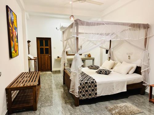a bedroom with a canopy bed and a bench at Nature House in Udawalawe