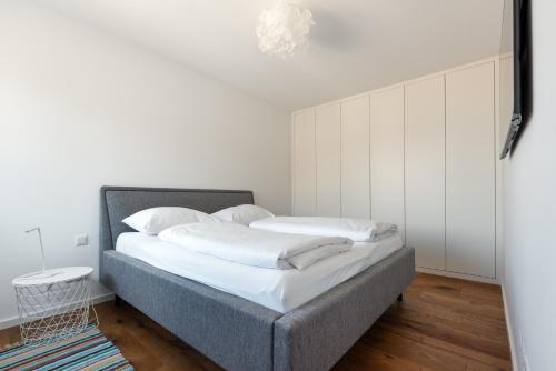 1 dormitorio con 1 cama con paredes blancas y suelo de madera en Stylisches Apartment in zentraler Grünruhelage mit Garagenplatz, en Viena