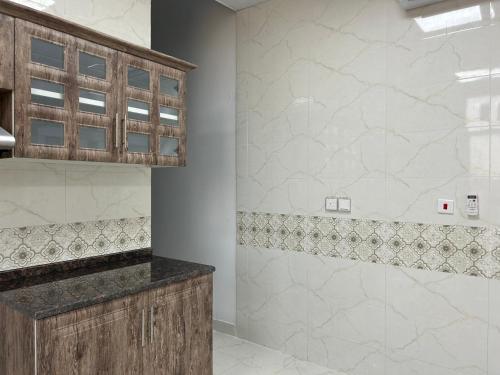 uma casa de banho com um lavatório e um chuveiro com azulejos brancos. em The Mountain Farm em Ras al-Khaimah
