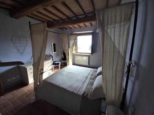 sypialnia z łóżkiem z baldachimem i oknem w obiekcie Country House - La casetta nel borgo w mieście San Venanzo