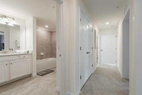 a white bathroom with a tub and a sink at STUNNING New Construction Condo close to everything! - Condo Coastal Soul - Roelens Vacations in Fort Myers Villas