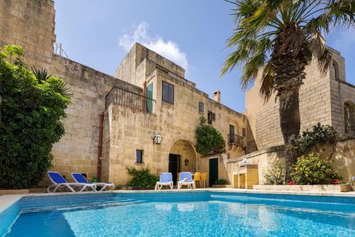 a house with a swimming pool in front of a building at Gozo Escape in Għasri