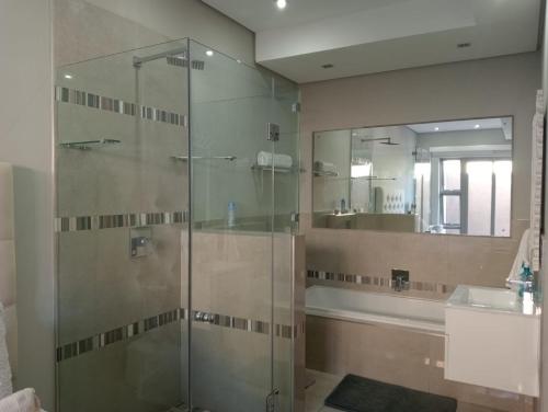 a bathroom with a glass shower and a sink at Stylish modern 2 bed apartment in Shaka's Rock in Ballito