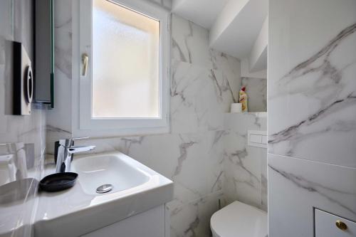 une salle de bain blanche avec un lavabo et une fenêtre dans l'établissement Magnificent 1-bedroom apartment Port Deauville, à Deauville