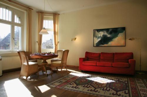 een woonkamer met een rode bank en een tafel bij Villa Daheim - FeWo 02 in Kolpinsee