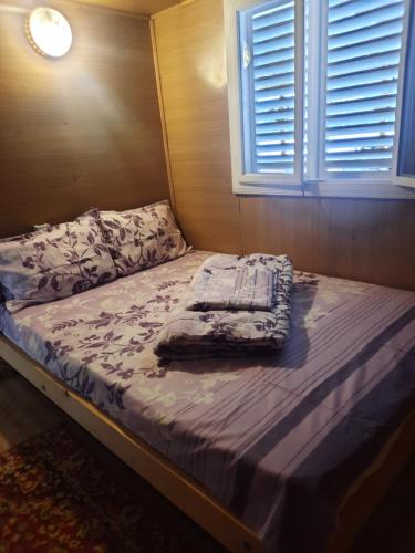 an unmade bed in a bedroom with a window at Ponton Maximilian in Poiana Cîrnului