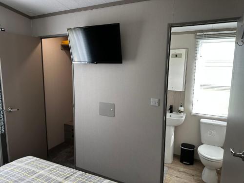 a small bathroom with a toilet and a refrigerator at Fairway 6 Lilliardsedge Caravan Hire in Jedburgh