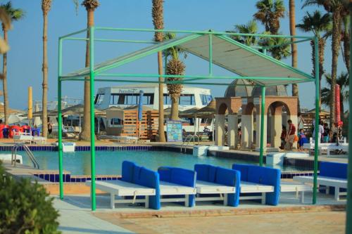 Mashrabiya Hotel في الغردقة: مسبح به مقاعد زرقاء وبيضاء وأشجار نخيل