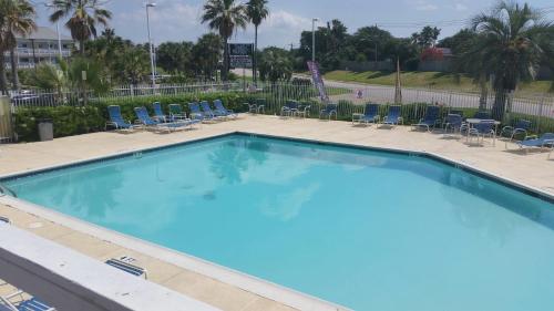 a large blue pool with chairs and palm trees at Inn at the Waterpark in Galveston
