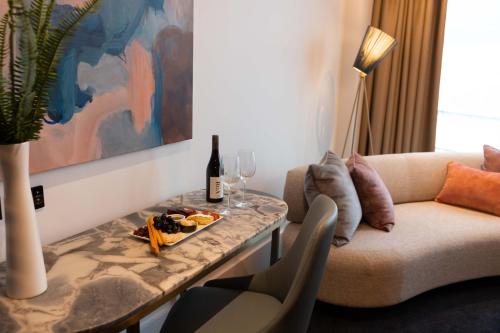 a living room with a couch and a table with wine glasses at Horizon by SkyCity in Auckland