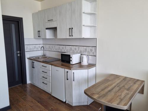 a kitchen with white cabinets and a wooden table at Apart Panorama in Lviv