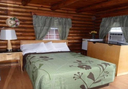 a bedroom with a bed in a log cabin at Seven Dwarfs Motel & Cabins in Lake George