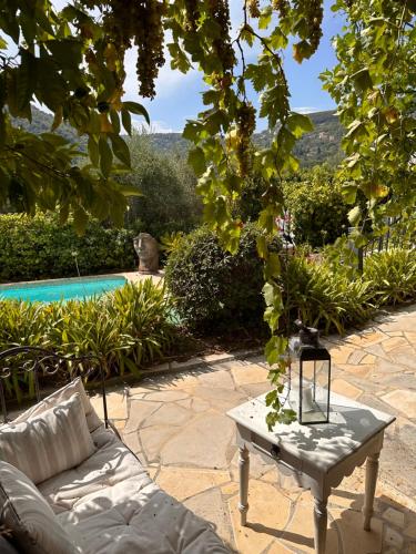 a couch and a table next to a pool at Bastide Aïna SPA et piscine in Grasse