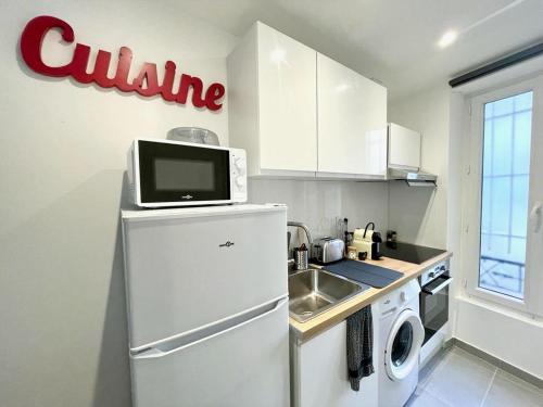 La cuisine est équipée d'un réfrigérateur blanc et d'un four micro-ondes. dans l'établissement SYDEL, à Paris