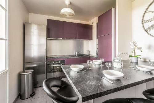 a kitchen with purple cabinets and a counter with bowls on it at Flat with terrace near Disneyland Paris - Welkeys in Bailly-Romainvilliers
