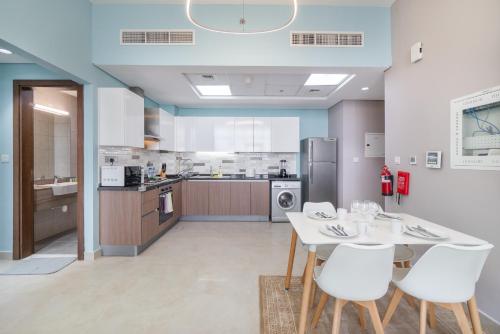 a kitchen with a white table and white chairs at Trinity Holiday Homes - Spacious Modern Living 1BR & 2BR Unique Apartment in Dubai