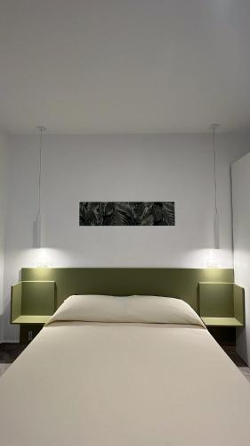 a bedroom with a white bed and two green shelves at B&b Villa Jasmine in Palinuro