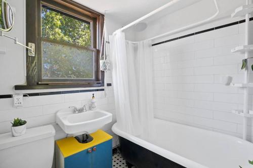 uma casa de banho branca com um lavatório e uma banheira em Rare find in Kitsilano! em Vancouver
