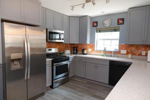 a kitchen with white cabinets and a stainless steel refrigerator at AMAZING!!!! Luxury 5BR, Steps to beach and Fun! Fully Renovated Beach house! in Atlantic City