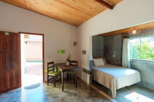 a bedroom with a bed and a desk and a window at Vita Chalés, na avenida central in Alto Paraíso de Goiás