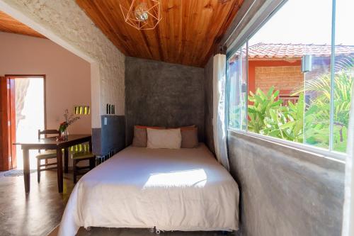 um quarto com uma cama e uma grande janela em Vita Chalés, na avenida central em Alto Paraíso de Goiás
