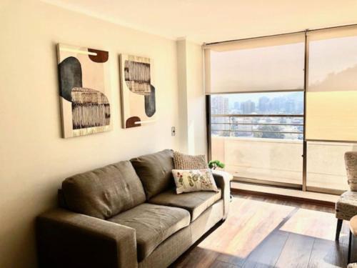 sala de estar con sofá y ventana grande en Lindo y acogedor departamento en Bellavista, en Santiago
