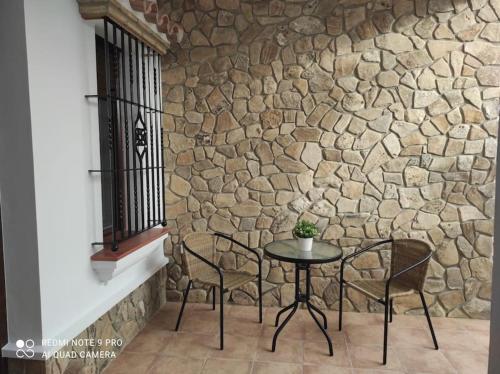 una mesa y sillas frente a una pared de piedra en Casa La Alquería en Chiclana de la Frontera