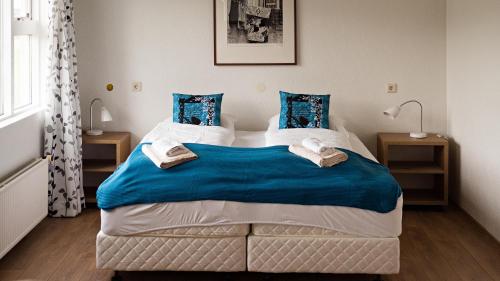 a bedroom with a large bed with blue sheets at Framtid Apartments and Holiday Homes in Djúpivogur