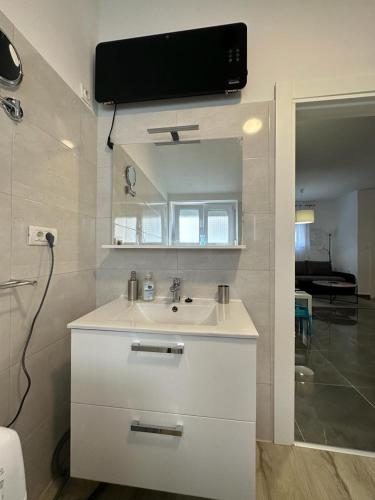 baño con lavabo y TV en la pared en Apartments Stinjan, en Pula