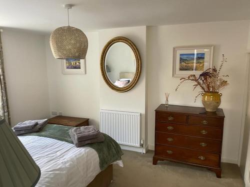 a bedroom with a bed and a mirror and a dresser at Cybil's Retreat - Renovated 2 bedroom house with enclosed garden in Uppingham