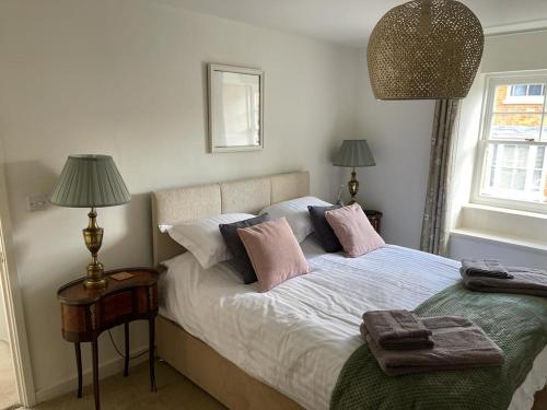 a bedroom with a bed with pink pillows on it at Cybil's Retreat - Renovated 2 bedroom house with enclosed garden in Uppingham