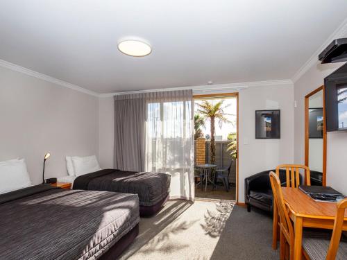 Habitación de hotel con 2 camas, escritorio y mesa en ASURE Chelsea Gateway Motor Lodge en Westport
