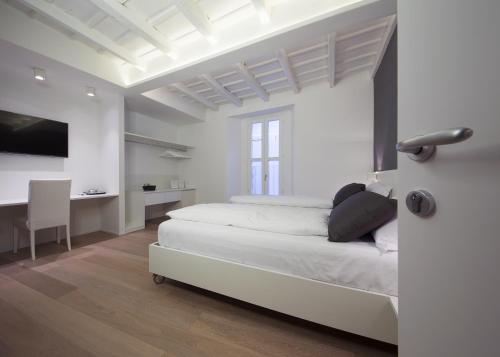 a white bedroom with a bed and a desk at Como Luxury Rooms in Como
