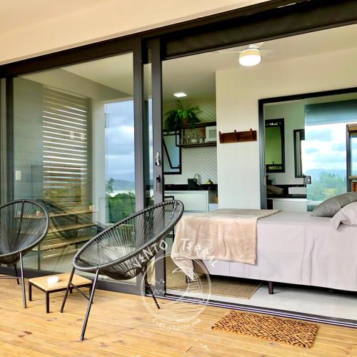 a bedroom with a bed and two chairs at VENTO TERRAL SURF STUDIOS in Imbituba