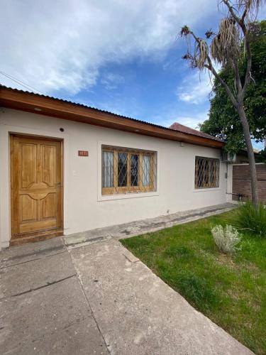 a white house with a wooden door and a yard at Casa 2 habitaciones en barrio céntrico in San Rafael