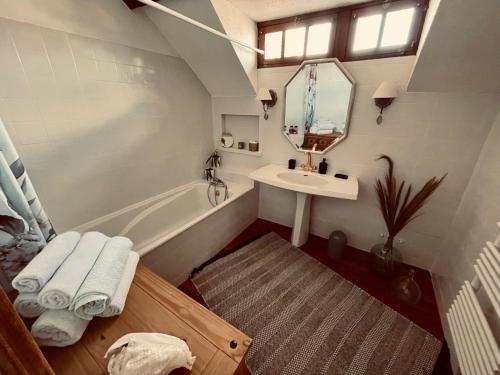 La salle de bains est pourvue d'un lavabo, d'une baignoire et d'un miroir. dans l'établissement Le Mas aux Papillons, à Vendat