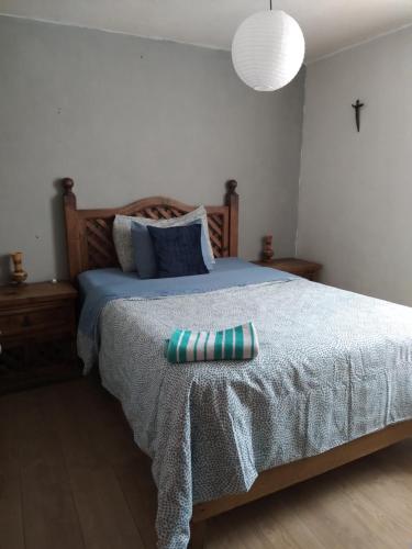 1 cama con colcha azul y almohada en Depa Cholulita, en Cholula
