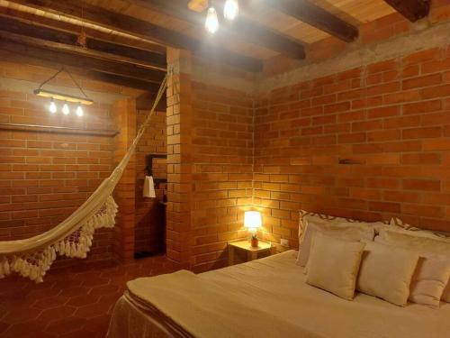 een slaapkamer met bakstenen muren, een bed en een lamp bij Casa del Rio in the Andes in Gualaceo